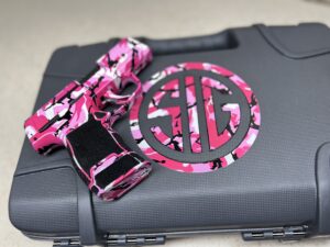 Sig Sauer P365 with pink camouflage design resting on a matching SIG-branded case.