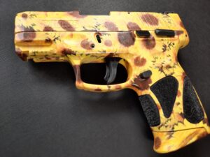 Taurus G3C gun customized with a Sunflower pattern as part of the pink gun collection for 2025. The stipple is untouched and the black looks incredible beside the yellow colors in the frames pattern