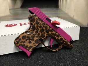 Ride side view of the custom ruger lcp .380 pistol customized in magenta solid color on the firearm slide, trigger, and magazine, while boasting the vivid Cheetah print on the firearms frame