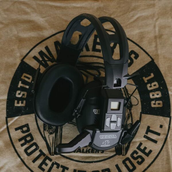 image of the walker's recon bluetooth walkie talkie attached to a pair of walker's ear muffs. View is from the left side angle that showcases the digital screen and its buttons.